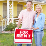 Couple Standing By For Rent Sign Outside Home